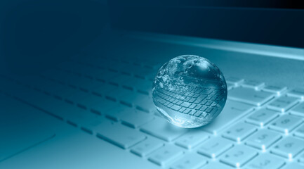 Fototapeta na wymiar Glass globe on blured laptop keyboard 