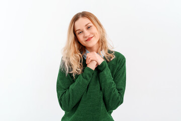Portrait of cute young blonde woman smiling, standing hopeful, anticipating, wishing to have smth, daydreaming, wears casual clothes. Indoor studio shot on white background