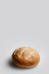 Round loaf of wheat bread on sourdough on a light background, vertical frame with space for text