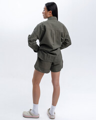 Beautiful Asian girl in a green linen casual suit posing against a white wall in a photo studio