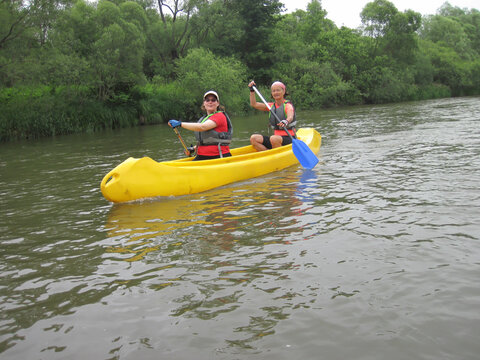 Two female canoeists rafting down a river in cloudy weather