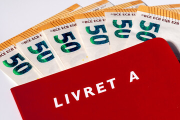 France: Gros plan d'un livret A avec plusieurs billets de 50 euros. Le livret A est un compte...