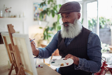Mature man with beard painting at easel