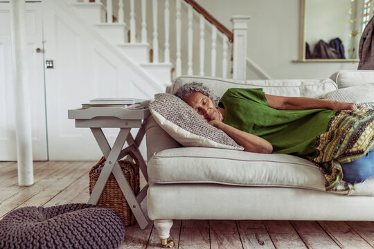 Serene senior woman napping on living room sofa