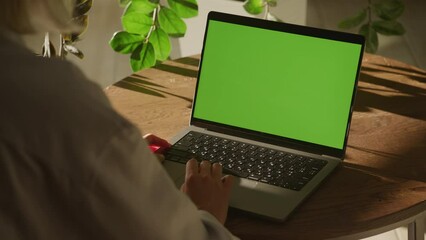 Handheld close up of a woman scrolling on a laptop computer touchpad with green screen chroma key