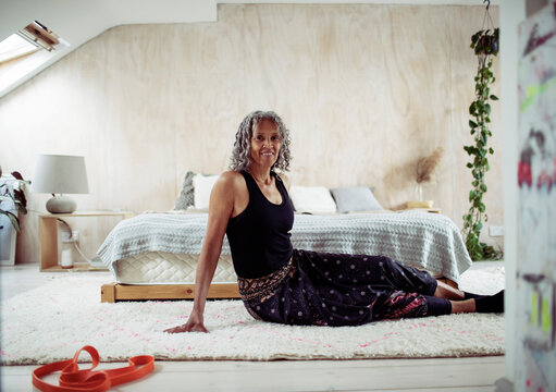 Portrait confident senior woman stretching on bedroom floor