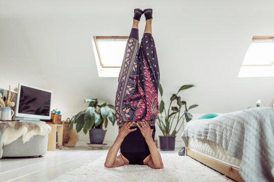 Woman doing yoga shoulder stand on bedroom floor