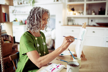 Happy senior woman painting at easel