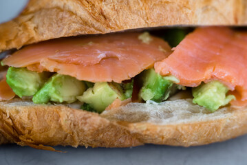 Fresh croissant with salmon and avocado. Healthy and tasty breakfast. Healthy diet. Close-up.