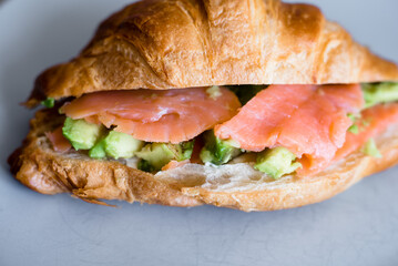 Fresh croissant with salmon and avocado. Healthy and tasty breakfast. Healthy diet. Close-up.