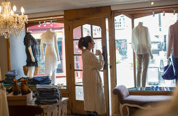 Female boutique owner drinking coffee at shop window