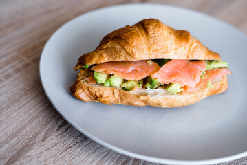 Fresh croissant with salmon and avocado. Healthy and tasty breakfast. Healthy diet. Close-up.