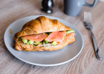 Fresh croissant with salmon and avocado. Healthy and tasty breakfast. Healthy diet. Close-up.