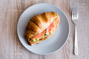 Fresh croissant with salmon and avocado. Healthy and tasty breakfast. Healthy diet. Close-up.
