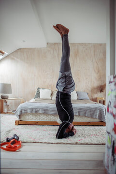 Mature man practicing headstand on bedroom rug