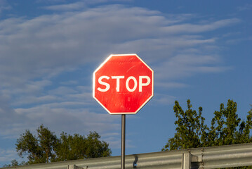 Red Stop Sign with Blue Sky and Clouds Background of the road