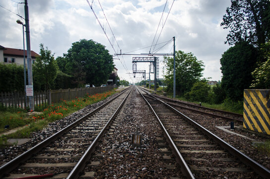 I binari ferroviari scorrono paralleli all'infinito sotto un cielo nuvoloso