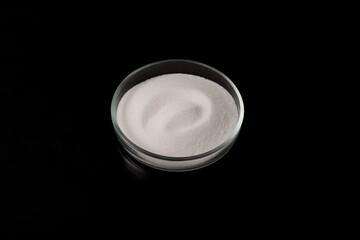 Sodium chlorate. White crystalline powder in a petri dish on a dark background. Chemical inorganic...