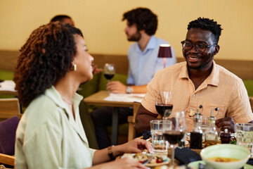 A multicultural couple having fun at the dinner table in a restaurant.