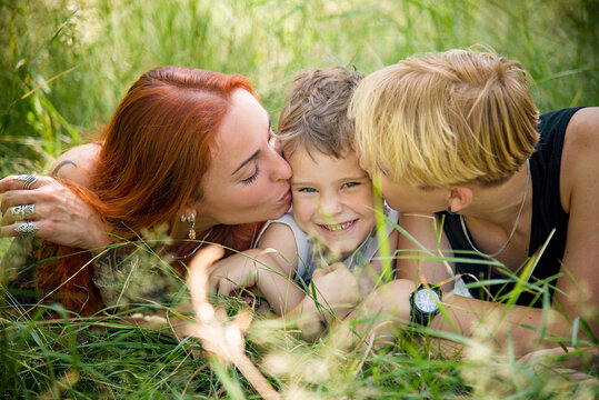 happy mother and sons having fun in the park and  lying on grass
