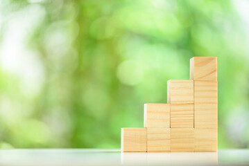 Square wood cubes are arranged in ascending stacks on a table. Cubes are placed in increasing order to represented an upward business trend or upward economic growth. Dices are put in ascending order.