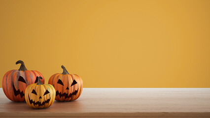 Halloween carved pumpkins on wooden table isolated on yellow colored background. Halloween backdrop with copy space for text. Autumn decoration