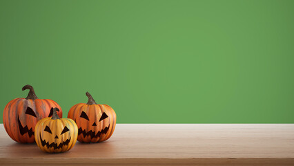 Halloween carved pumpkins on wooden table isolated on green colored background. Halloween backdrop with copy space for text. Autumn decoration