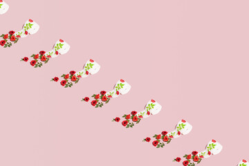 Toilet paper rolls creatively decorated with fresh green leaves and red roses. Pastel pink background. 