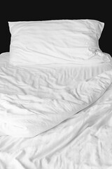 Cover bed sheets were wrinkled after waking up. Soft fabric pillow and blankets in a cozy bedroom. White messy mattress background. Sleep and relaxation. Untidy crease duvet. Housekeeping concept.