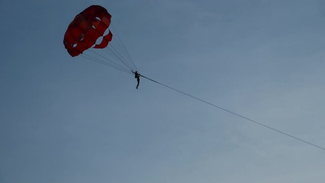 People flying on parachute wide. Parachute flying over water. Parasailing in sea across seaside. Summer vacation water sports leisure
