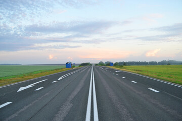 Fototapeta na wymiar An empty paved road at dawn in a field