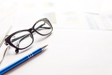 Documents with pen and eyeglasses on office table. Close up shot. Concept of concluding. Focus on glasses, blurred background. Business workplace, lawyer's workplace