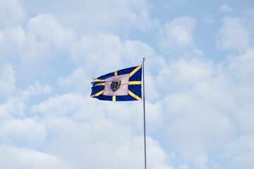Bandeira da cidade de Anápolis balançando ao vento com céu nublado ao fundo. Foto feita em...