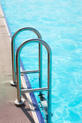 metal staircase to a beautiful swimming pool. Blue bright water background