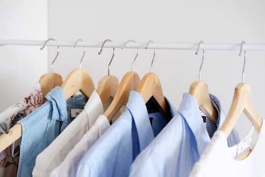 Men's and women's clothing hangs on hangers in white protective covers