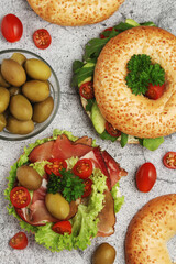 Sesame bagels with tomatoes, ham and olives