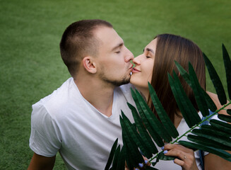 Happy lovely young kissing couple in love spending time outdoors in park