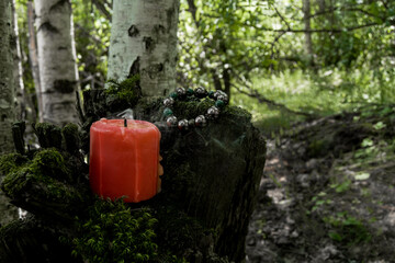 burning red candle, a symbol of the moon, an amulet lying on moss on a dark natural background....