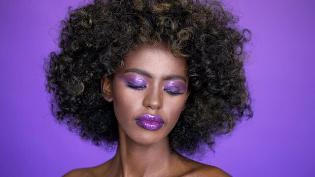 Portrait of beautiful african american female model with afro hair and glowing purple makeup