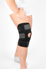 Knee Support Brace on leg isolated on white background. Elastic orthopedic orthosis. Anatomic braces for knee fixation, injuries and pain. Protective knee joint bandage sleeve. Trauma, rehabilitation.