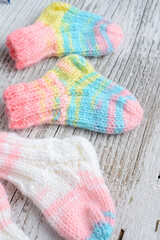 colorful and small baby socks, made of cotton yarn, on vintage white wooden background