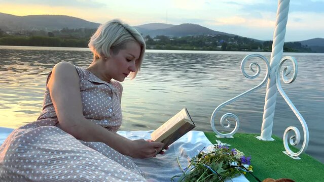 A girl on a raft reads a book in the middle of the lake