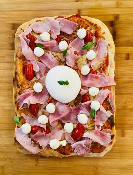 Roman pizza, variant of classic Italian pizza with san marzano tomato and mozzarella di bufala on wooden background