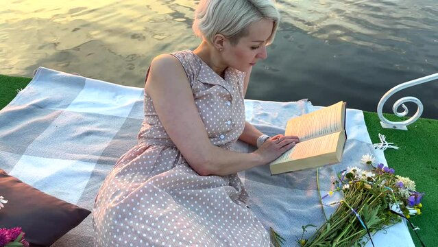 The girl turns the page of the book. The Model lies on the raft