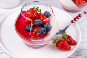 Fruit jelly dessert or panna cotta with fresh strawberries and blueberries, banner, copy space, menu, on white background