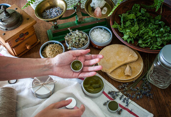 Women's hands holding a tin jar of homemade salve. Home herbalism and cosmetics. Natural homemade...