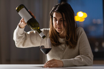 alcoholism, alcohol addiction and people concept - drunk woman or female alcoholic drinking red wine at home