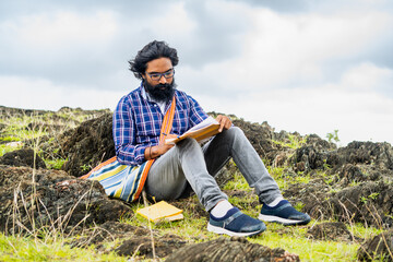 Thoughtful beard author seriously writing novel while sitting on top of hill - conept of artist, creativity and imagination - obrazy, fototapety, plakaty