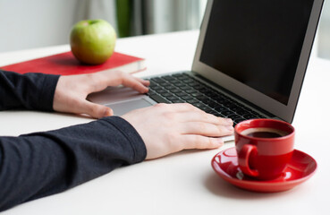 Man hands on laptop keyboard with notebook, green apple and red cup of coffee on white table - 517161559