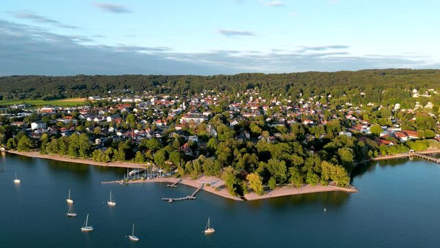 Aerial view flying drone of town Herrsching at Ammersee lake, luxurious residential area with high class marina and beautiful view. Lakeside sailing harbor near munich in Germany, recreation area